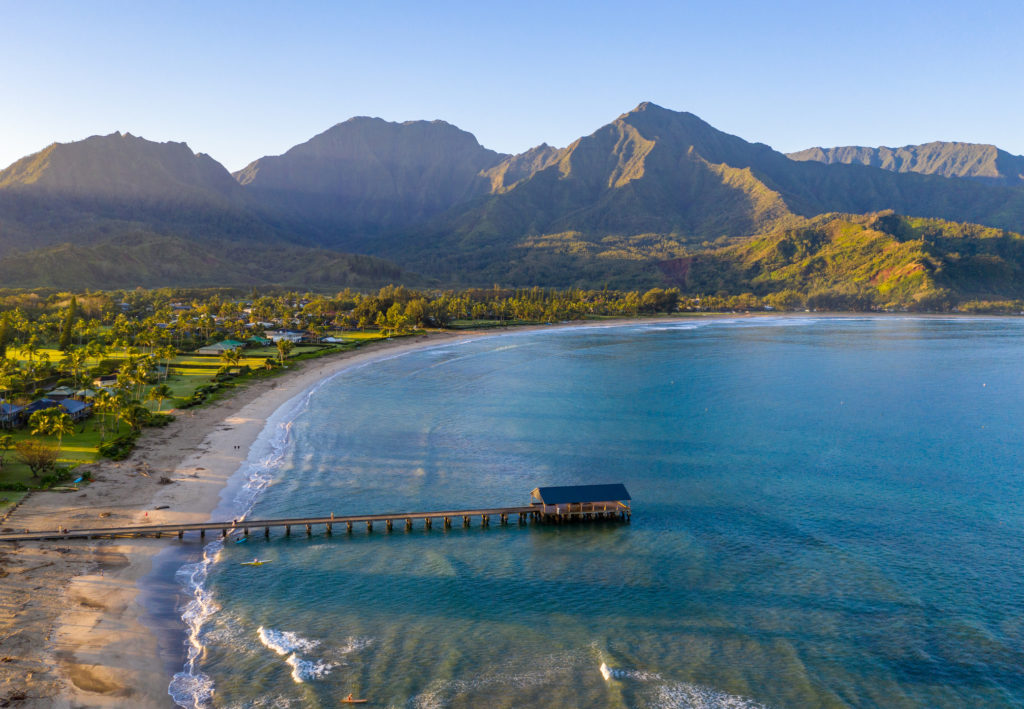 Aerial panoramic image at sunrise off the coast over Hanalei Bay and pier on Hawaiian island of Kauai